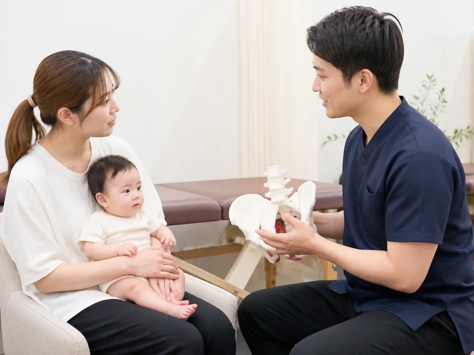 産後の骨盤の状態を模型で説明を受ける母親