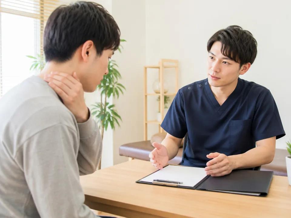交通事故後の症状を相談する患者と整骨院スタッフ