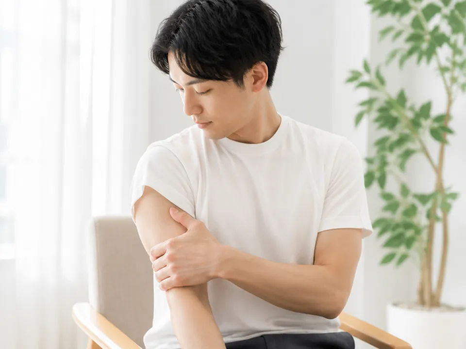 上腕二頭筋と肩の前側を軽く触ってセルフチェックする様子