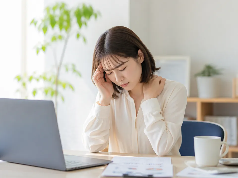 肩こりと頭痛でこめかみを押さえる人