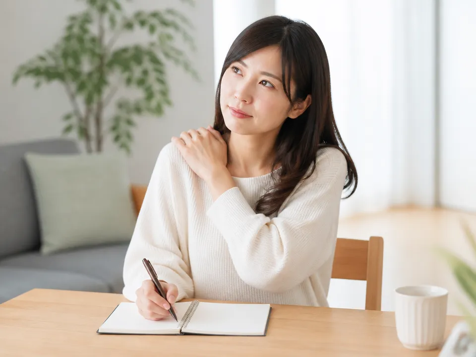 胸の重さと肩こりの症状メモを取り相談先を検討する女性