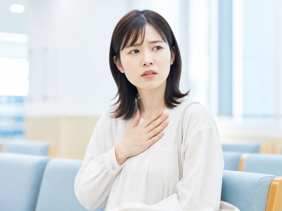 胸の強い痛みや息苦しさで医療機関受診を検討する女性