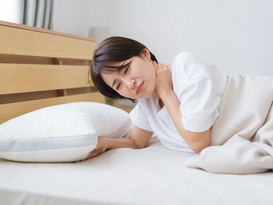 首や肩のこりと寝姿勢を気にしている人のイメージ