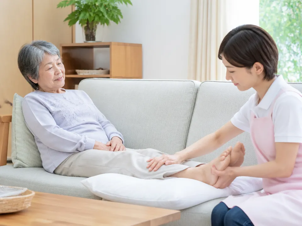 在宅介護で高齢者の足を高くして休ませながら家族がやさしくケアしている様子