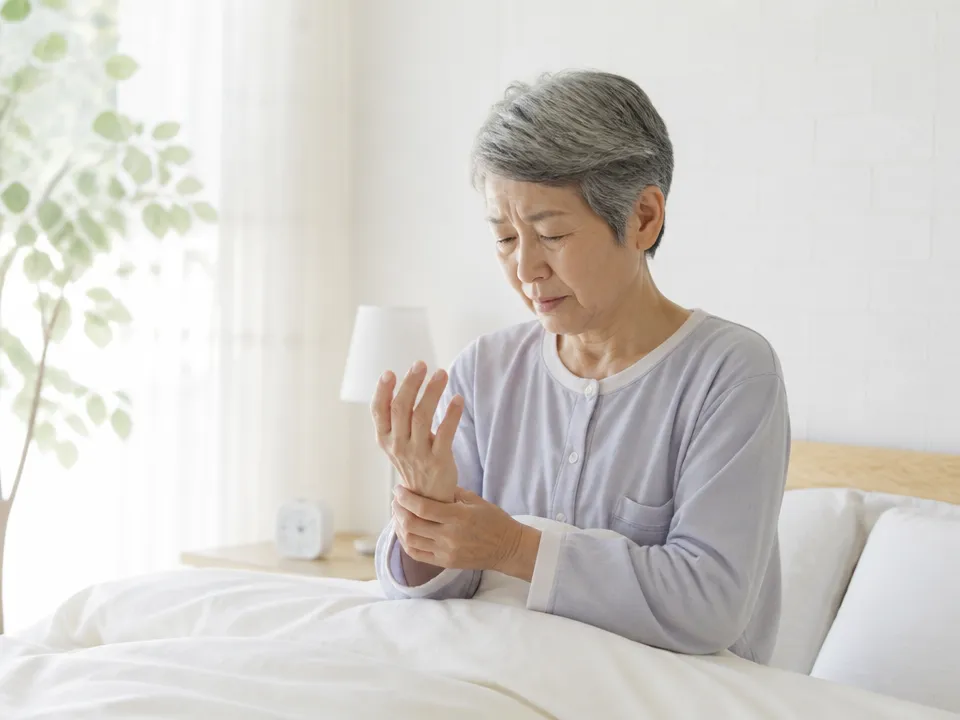 朝起きたときに手のしびれを気にしている高齢者の様子