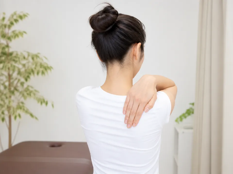 肩甲骨外側の張りや重さを手で触って確認する女性の背中