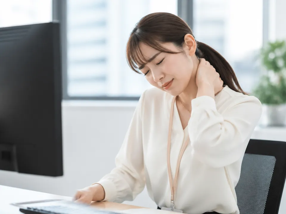 前かがみ姿勢でデスクワークをして首の付け根がこっている人