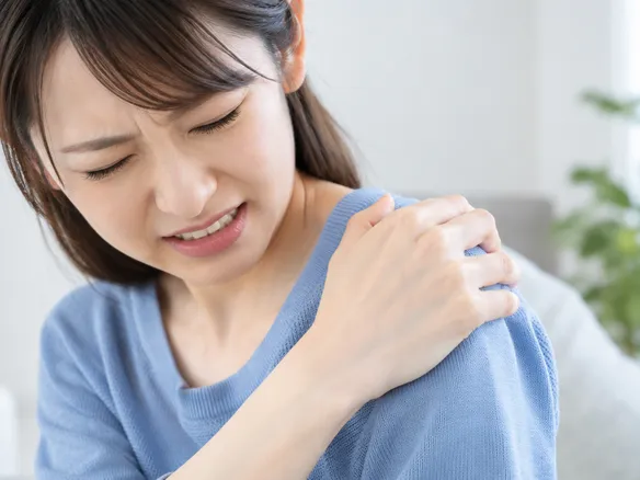 肩を強く揉んで痛そうにしている人