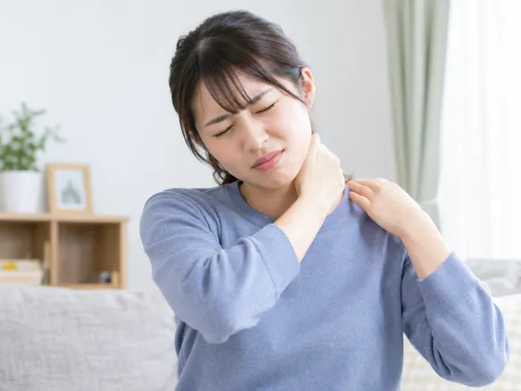 首を強く揉んでしまい表情をゆがめている人の様子