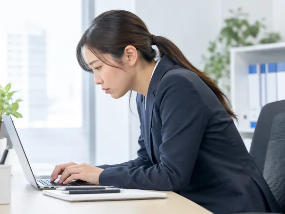 前かがみ姿勢でパソコンを見る人の首肩に負担がかかる様子