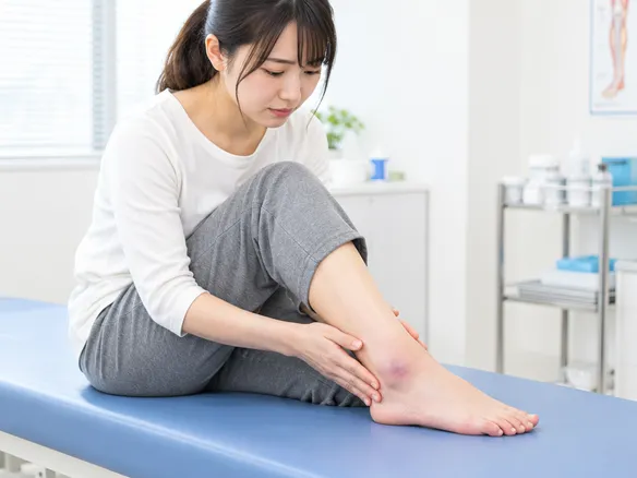 外くるぶしの下が腫れて足首を押さえる人の写真