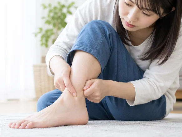 内くるぶしの下を指で押して痛みを確かめる様子