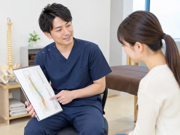 接骨院でカウンセリングを受ける人と説明する柔道整復師